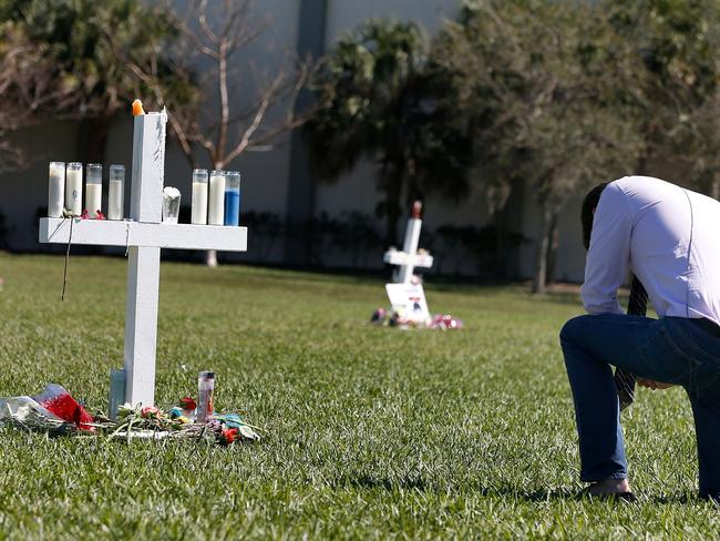 A mourner kneels in front of a memorial for the victims of the Marjory Stoneman Douglas High School shooting in a park in Parkland, Florida. Picture: AFP