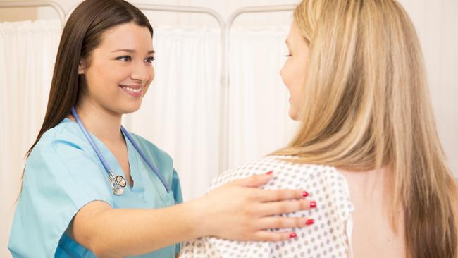 Mid-adult woman receives annual breast exam from her Latin descent gynecologist. Breast cancer awareness concept.