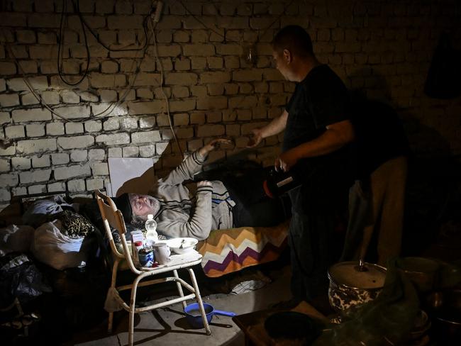 A man helps his father in the basement of their building, where they are both living, in Lysychansk. Picture: AFP