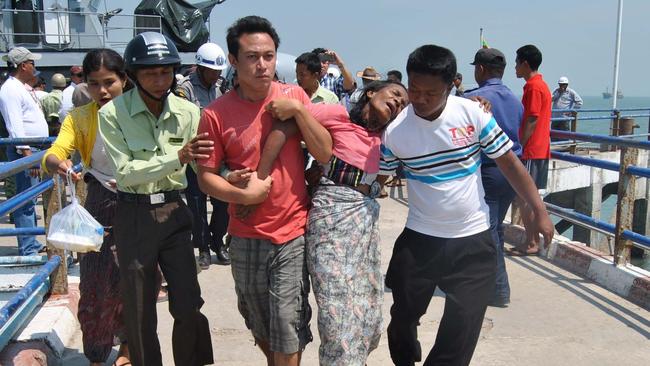 TOPSHOTS A survivor (2-R) from an overloaded ferry that sank is helped as she arrives at Kyaukphyu jetty in western Myanmar Rakhine state on March 14, 2015. Rescuers were frantically searching for survivors on March 14 after an overloaded ferry sank in rough waters off the coast of western Myanmar killing at least 21 and leaving dozens more missing. AFP PHOTO