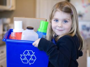 A young girl holding a recycling bin with empty plastic containers. Shallow DOF.