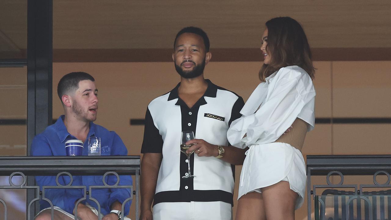 Nick Jonas speaks with John Legend and Chrissy Teigen at the gymnastics. Picture: Getty Images