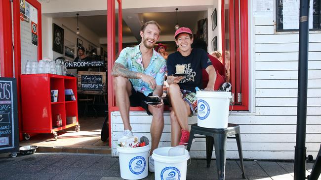 Hemingway's cafe manager Tommy Schoeb with Surf Rider Foundation Manly member Jude Furniss are encouraging people to fill a bucket with rubbish from the beach in return for a coffee. Picture: Richard Dobson