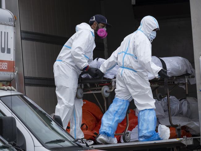 Workers move bodies to a refrigerated truck from the Andrew T. Cleckley Funeral Home in the Brooklyn borough of New York, Wednesday, April 29, 2020. Police responded to a report of human bodies in vehicles, which they determined were connected to the nearby funeral home. The New York Police Department notified the state Department of Health, which oversees funeral homes. The coronavirus pandemic has overrun most funeral homes and morgues in New York City. (AP Photo/Craig Ruttle)