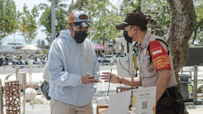 A security guard checks a visitor's vaccination certificate in Kuta on Thursday. Picture: Anggara Mahendra