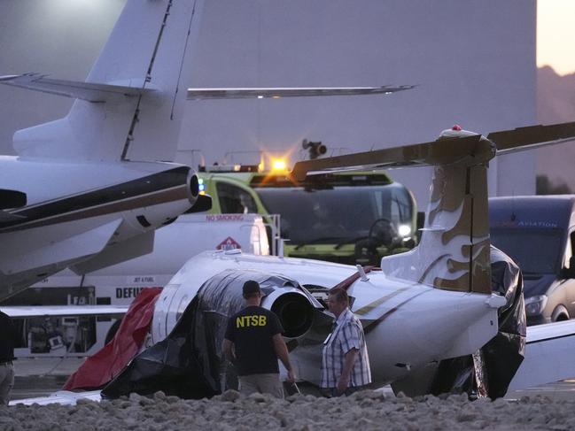 Investigators at the scene after a Learjet collided with a parked plane. Picture: AP