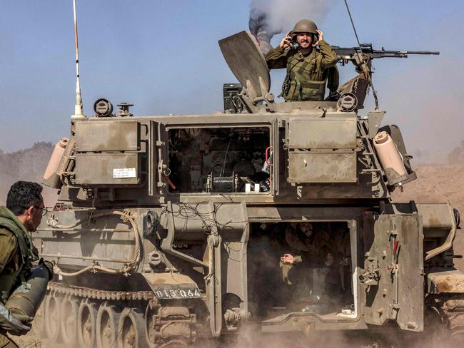 An Israeli army soldier carries rounds from a stockpile towards a stationed self-propelled artillery howitzer firing from a position near the border with the Gaza Strip in southern Israel on November 6, 2023 amid the ongoing battles between Israel and the Palestinian group Hamas in the Gaza Strip. (Photo by MENAHEM KAHANA / AFP)