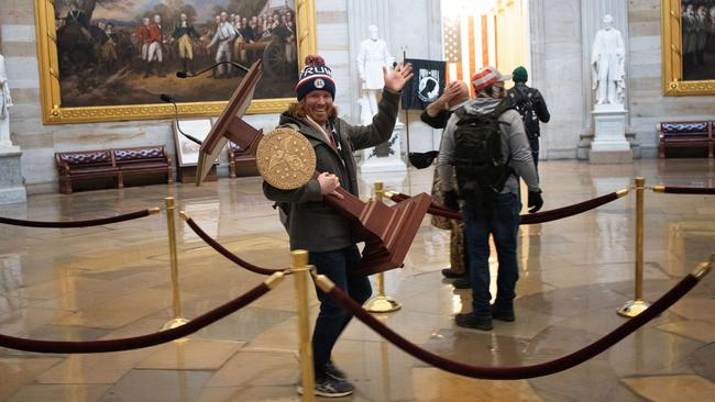 A pro-Trump insurgent smiles as he steals the lectern of US Speaker of the House Nancy Pelosi during the January 06 attack on the US Capitol. Picture: Win McNamee/Getty Images/AFP