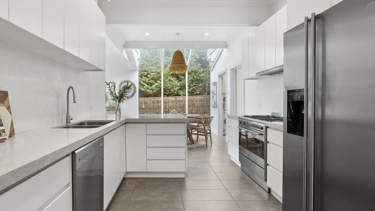 The kitchen overlooks a casual meals area set beneath an atrium-style window.