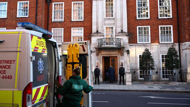 A paramedic opens the rear door of an ambulance as police officers stand guard outside the London Clinic. Picture: AFP