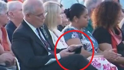 Scott Morrison on his phone during an Anzac Day service.