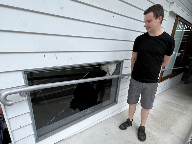 Three Tree Frogs owner Luke Synnott beside a broken window at his Helensvale cafe, where intruders broke in and stole a till and mobile phone. Picture: Keith Woods.