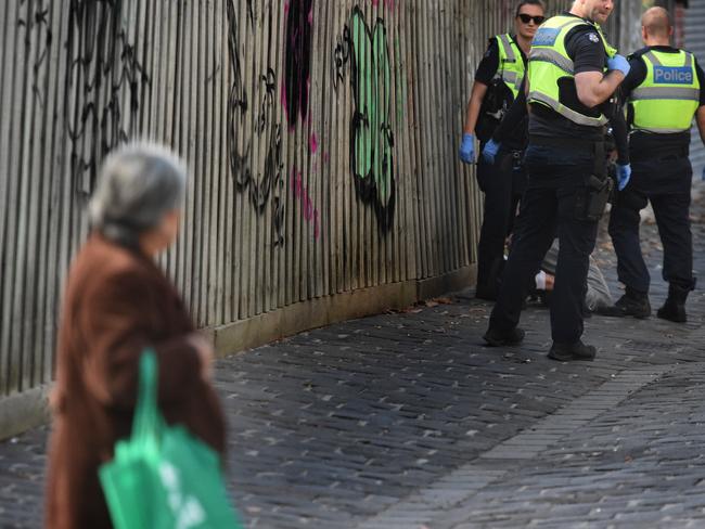 A woman watches on as police talk to a man. Picture: Tony Gough