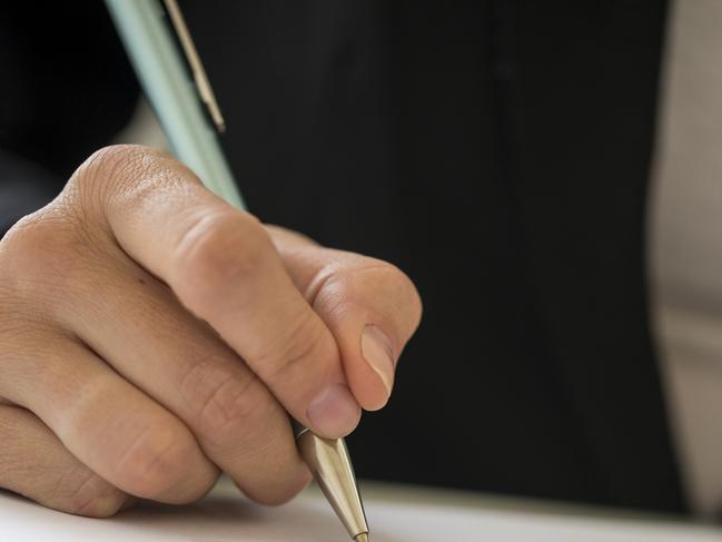 CAREERS: Low angle view of a woman signing contract with a pen.