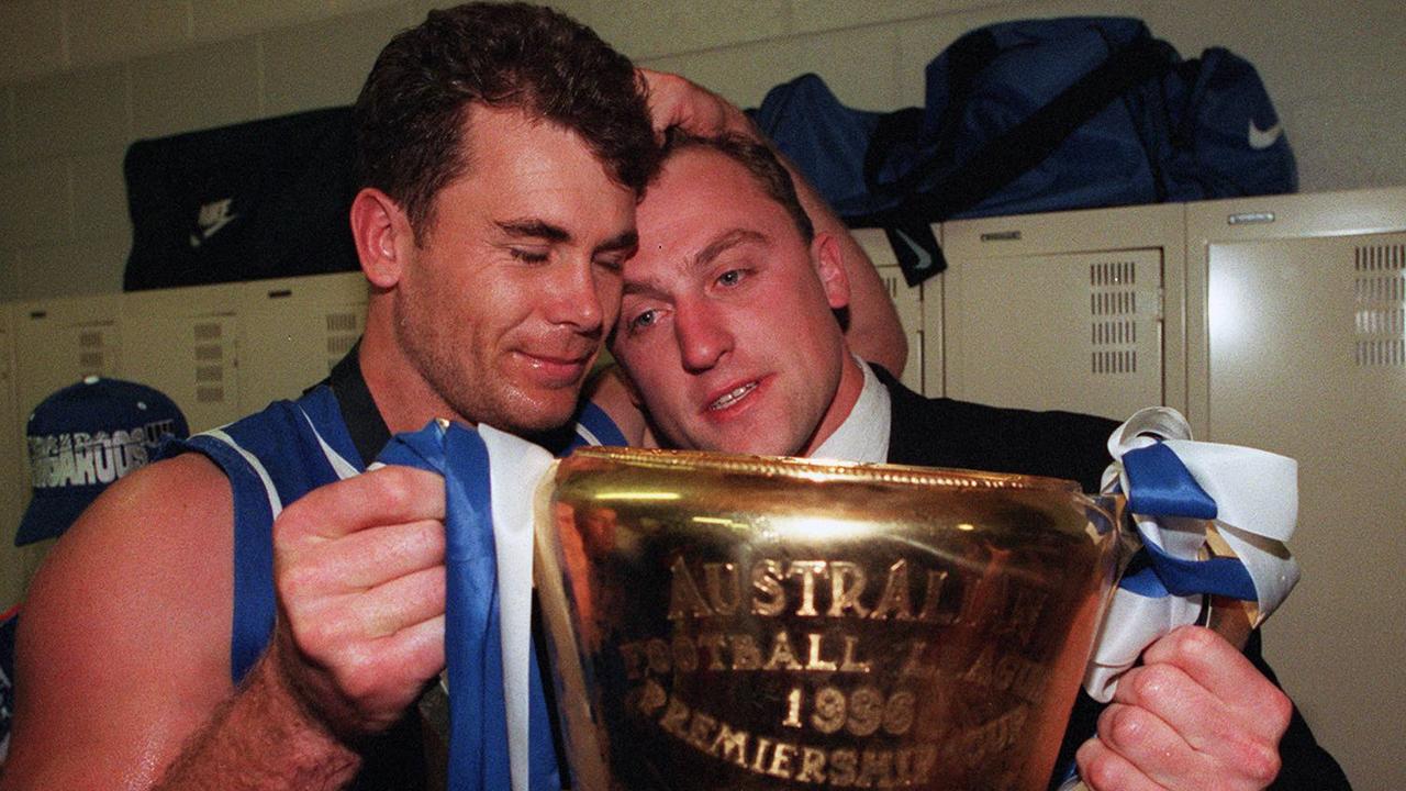 Recruited as part of the same deal in 1987, Carey and Longmire both became champions for North Melbourne. Carey and Longmire are pictured here after the Kangaroo’s flag win in 1996. Longmire missed the Grand Final due to injury. Photo: Brett Faulkner.