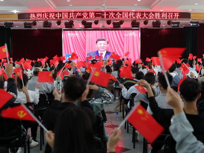 TOPSHOT - This photo taken on October 16, 2022 shows people waving national flags and Communist Party flags as they watch the opening session of the 20th Chinese Communist Party Congress in Huaibei, in Chinaâs eastern Anhui province. - President Xi Jinping hailed China's rise as a global power and demanded unity around his leadership on October 16, launching a Communist Party Congress that is set to rubber stamp his bid to rule for a historic third term. (Photo by AFP) / China OUT