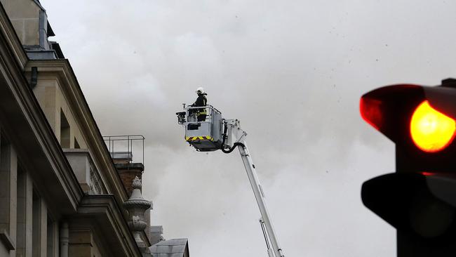 A French firefighter ... stands atop a fire ladder as a fire engulfed the top floor of Paris’ Ritz Hotel. Picture: AP