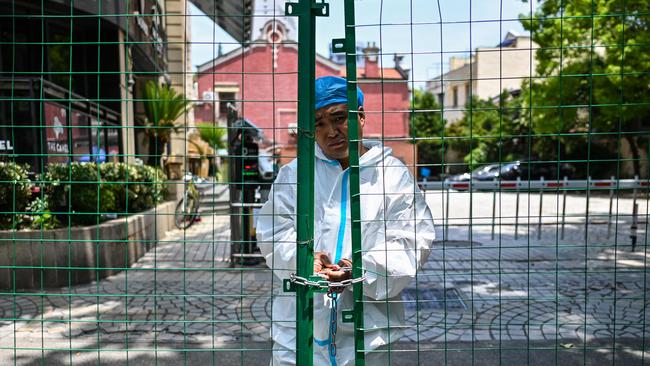 A worker padlocks fencing securing a residential area under Covid-19 lockdown in the Xuhui district of Shanghai. Picture: AFP.