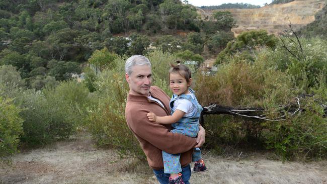 Residents Against White Rock Quarry chairman Demetrios (Jim) Bastiras of Skye with his daughter Artemis, 2, in Horsnell Gully Conservation Park, Mount Skye in background, quarry to the right in May 2021. Picture: Michael Marschall