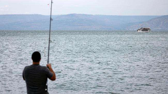 A man wearing a Jewish kippah skullcap fishes with a rod on the boardwalk of the Sea of Galilee in Israel's northern city of Tiberias on Sunday. Picture: AFP