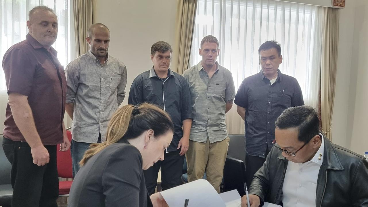 Michael Czugaj, second left, and Scott Rush, third left, appear alongside Martin Stevens, Matthew Norman and Si Yi Chen in this photo released by the Indonesian Coordinating Ministry for Legal, Human Rights, Immigration and Correctional Affairs, Indonesian and Australian officials sign handover documents. Picture: Indonesian Coordinating Ministry for Legal, Human Rights, Immigration and Correctional Affairs via AP