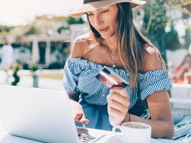 ESCAPE:  Beautiful young woman with laptop and credit card in the back yard in the summer Picture: Istock