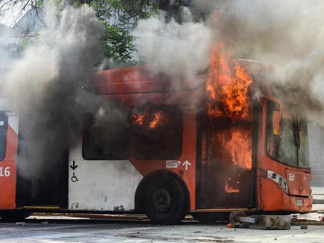 A bus burns down during clashes between protesters and the riot police in Santiago, on October 19, 2019. - Chile's president declared a state of emergency in Santiago Friday night and gave the military responsibility for security after a day of violent protests over an increase in the price of metro tickets. (Photo by Martin BERNETTI / AFP)