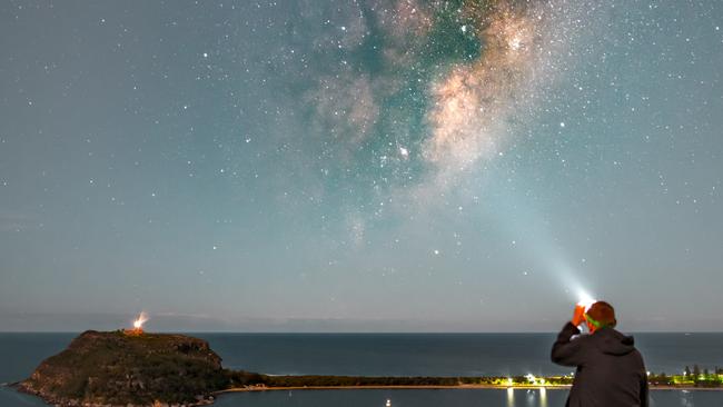 A man sitting at West Head lookout looking up to the Milky Way with the Barrenjoey Headland in the background. Palm Beach could become part of an Urban Night Sky Park — the first of its kind in Australia. Picture Greg Barber