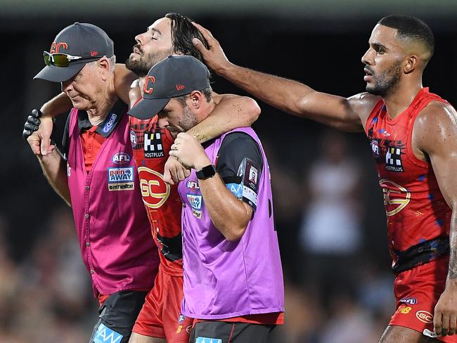 Weller is escorted from the field at TIO Stadium with a suspected ACL injury. Picture: Felicity Elliott/AFL Photos via Getty Images.