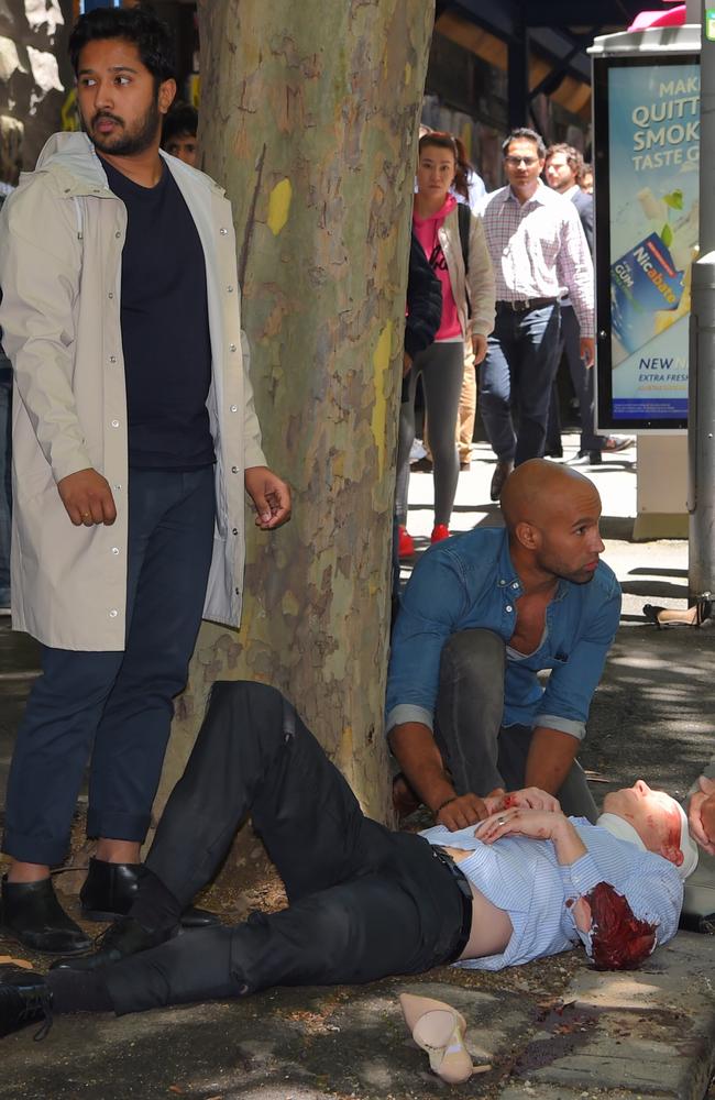 Bystanders help a man left bloodied on a footpath. Picture: Tony Gough