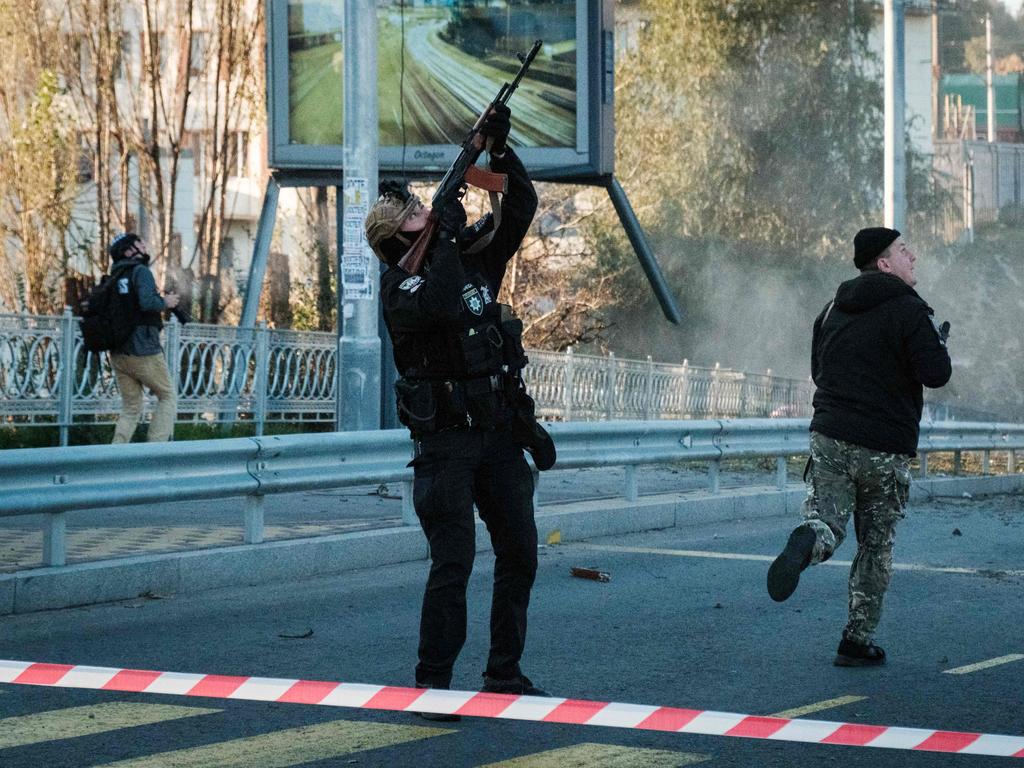 A police officer fires at a flying drone following attacks in Kyiv.
