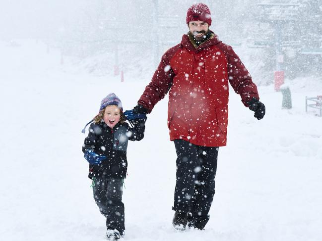 Paul Heginbothom and Erin Flynn with their children Lily (7 months) and George (3) at Thredbo in the snow on Wednesday. 9 June 2021Photo by Rohan Thomson