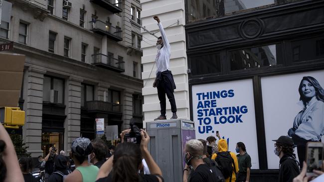 A demonstrator stands on a phone box in Fifth Avenue, Manhattan. Picture: AP