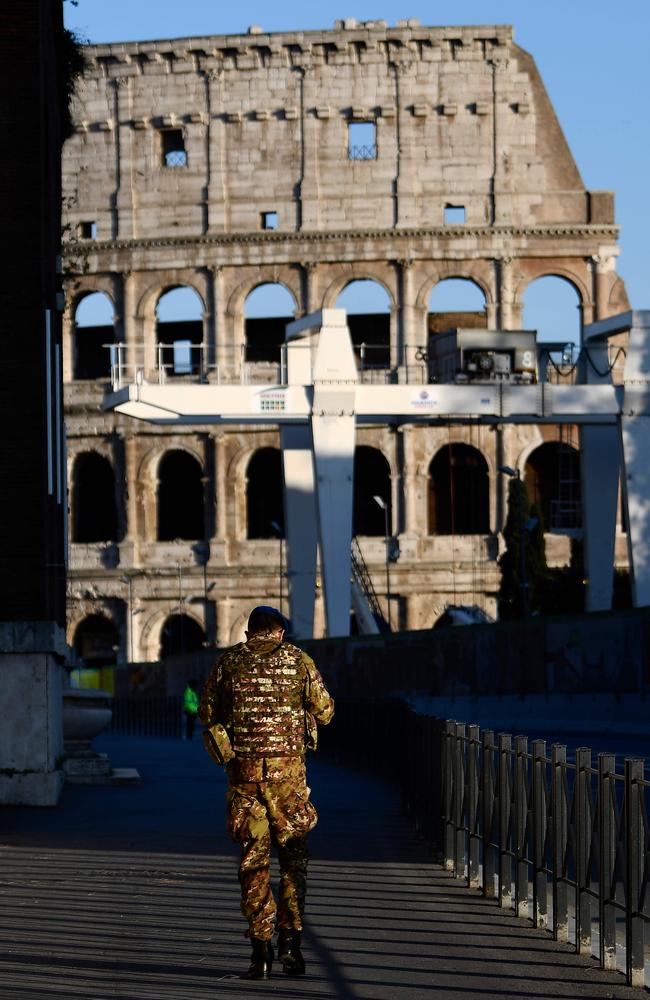 A military man walks towards the Colosseum monument along a deserted Via dei Fori Imperiali in Rome. Picture: AFP