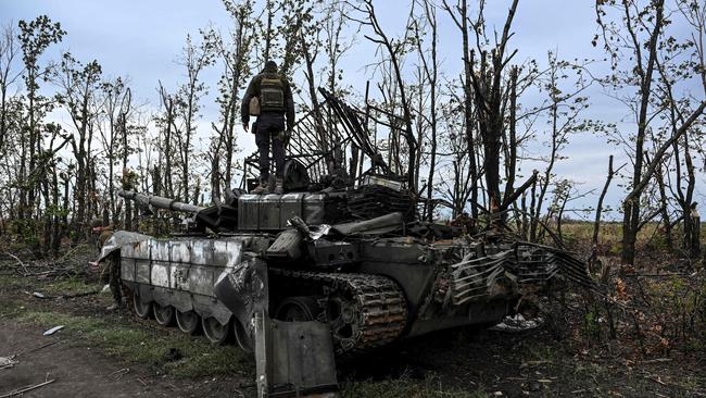 A Ukranian soldier stands atop an abandoned Russian tank near a village on the outskirts of Izyum, Kharkiv Region, where Ukrainian forces have retaken territory in recent weeks.