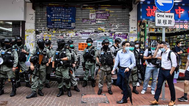 Pedestrians walk past a group of riot police standing guard in a front of a shop in the Causeway Bay district of Hong Kong. Picture: AFP