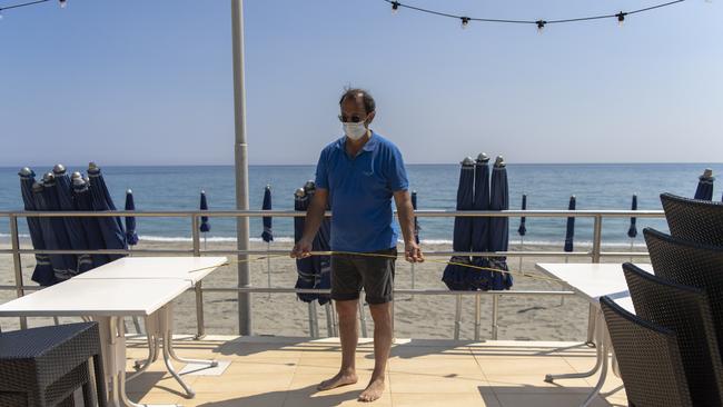 The owner of a restaurant checks the distance between tables to comply with rules to limit the spread of COVID-19, in Alassio, by the Italian riviera. Picture: AP