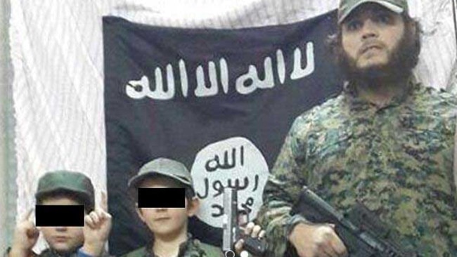 Khaled Sharrouf and boys believed to be his three sons (one not visible) stand in front of the Islamic State flag in an image posted on Twitter. Source: Supplied