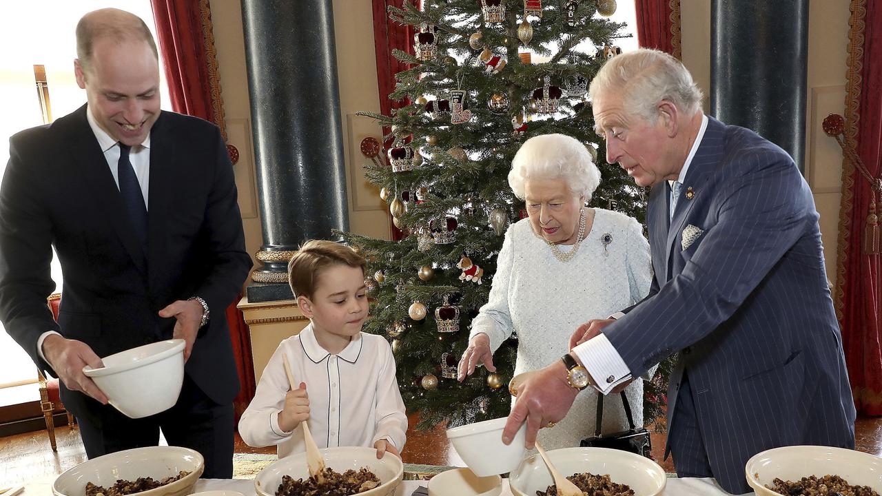 Britain's Queen Elizabeth, Prince Charles, Prince William and Prince George smile as they prepare special Christmas puddings in the Music Room at Buckingham Palace. Picture: Chris Jackson/Buckingham Palace via AP