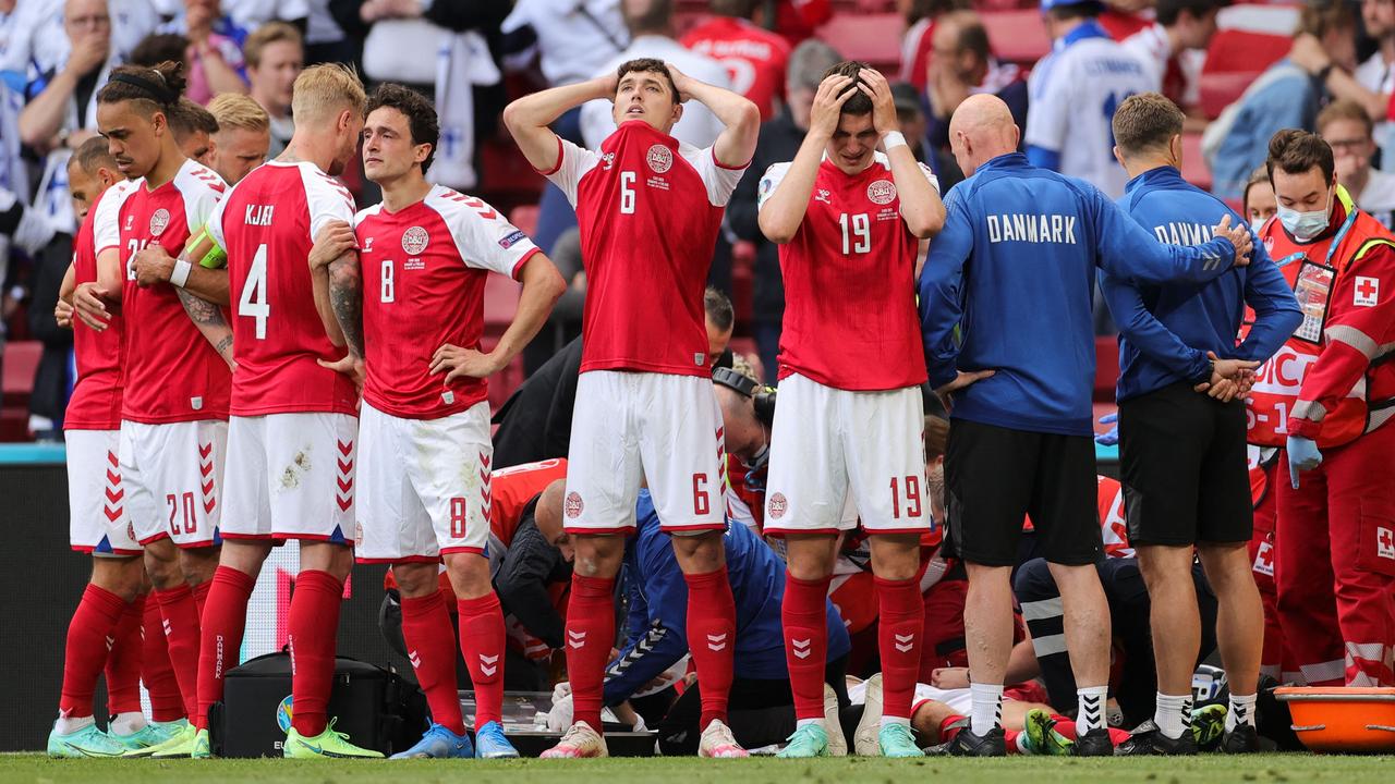TOPSHOT – Denmark's players react as paramedics attend to Denmark's midfielder Christian Eriksen after he collapsed on the pitch during the UEFA EURO 2020 Group B football match between Denmark and Finland at the Parken Stadium in Copenhagen on June 12, 2021. (Photo by Friedemann Vogel / POOL / AFP)