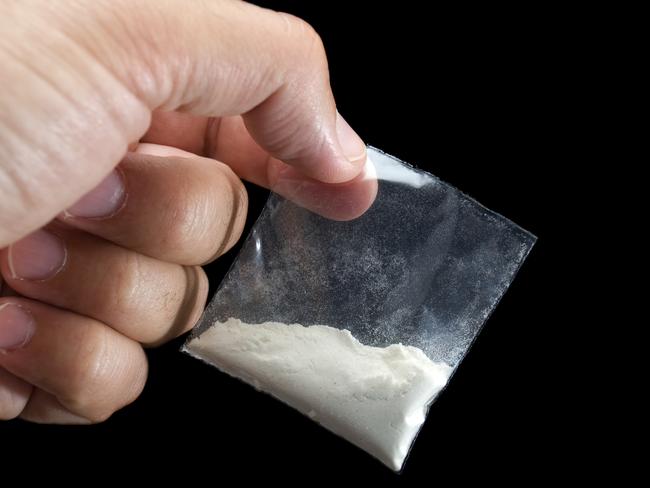 Generic photo of cocaine. Dealer is holding drug bag in his hand on a black background. Picture: iStock