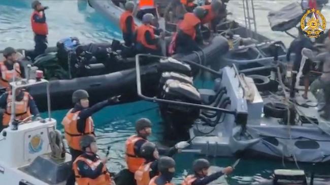 Chinese coast guard personnel threaten Phillipines navy sailors off Second Thomas Shoal last month. Picture: AFP