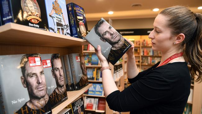 Alannah Woods, an assistant floor manager at Dymocks bookstore, places Shane Warne's new autobiography titled "Top Spin" on a bookshelf in Melbourne on October 5, 2018. - Australian great Shane Warne has endorsed one of the most controversial figures in cricketing history, while also renewing his decades-old feud with former captain Steve Waugh.  Warne, Test cricket's second most prolific wicket-taker with 708 scalps, revealed a his admiration for Douglas Jardine, who led England's "Bodyline" tour in his new book "No Spin". (Photo by William WEST / AFP)