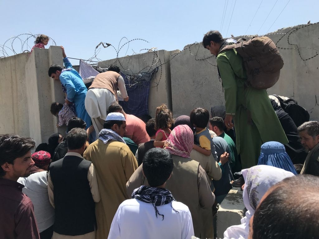 People struggle to cross the boundary wall of Hamid Karzai International Airport to flee the country. Picture: STR/NurPhoto via Getty Images