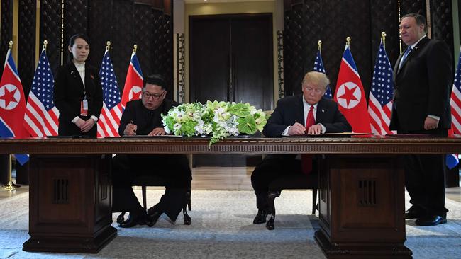 Kim Jong-un and Donald Trump sign documents as US Secretary of State Mike Pompeo and the North Korean leader's sister Kim Yo Jong look on. Picture: AFP