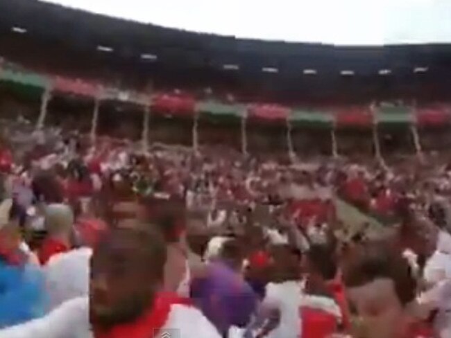 Crowd members run as they see the bull charging in their direction.