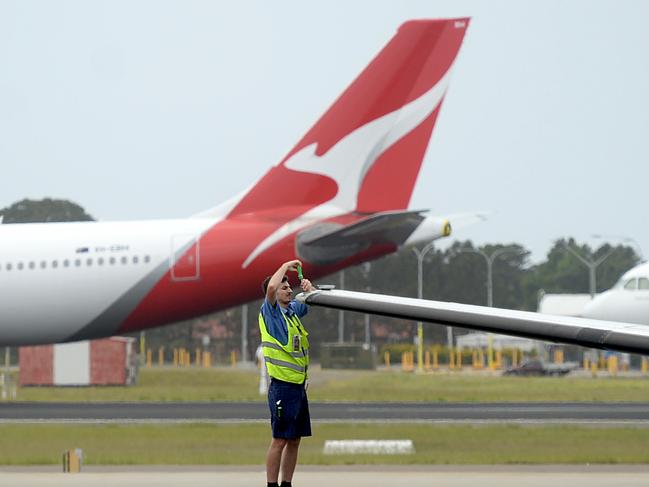 SYDNEY, AUSTRALIA - NewsWire Photos DECEMBER 2, 2020. A man works on a plane as Qantas planes sit idle at Sydney Domestic airport.Picture: NCA NewsWire / Jeremy Piper