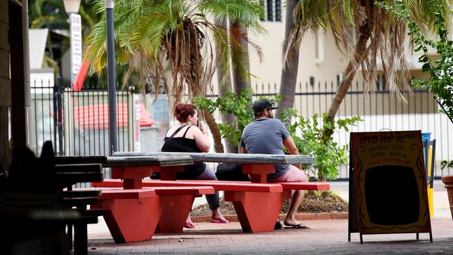 People (not involved in the incident) sit at table and chairs next to the Darwin Transit Bus Centre, where a man impaled himself overnight. Picture: Elise Derwin