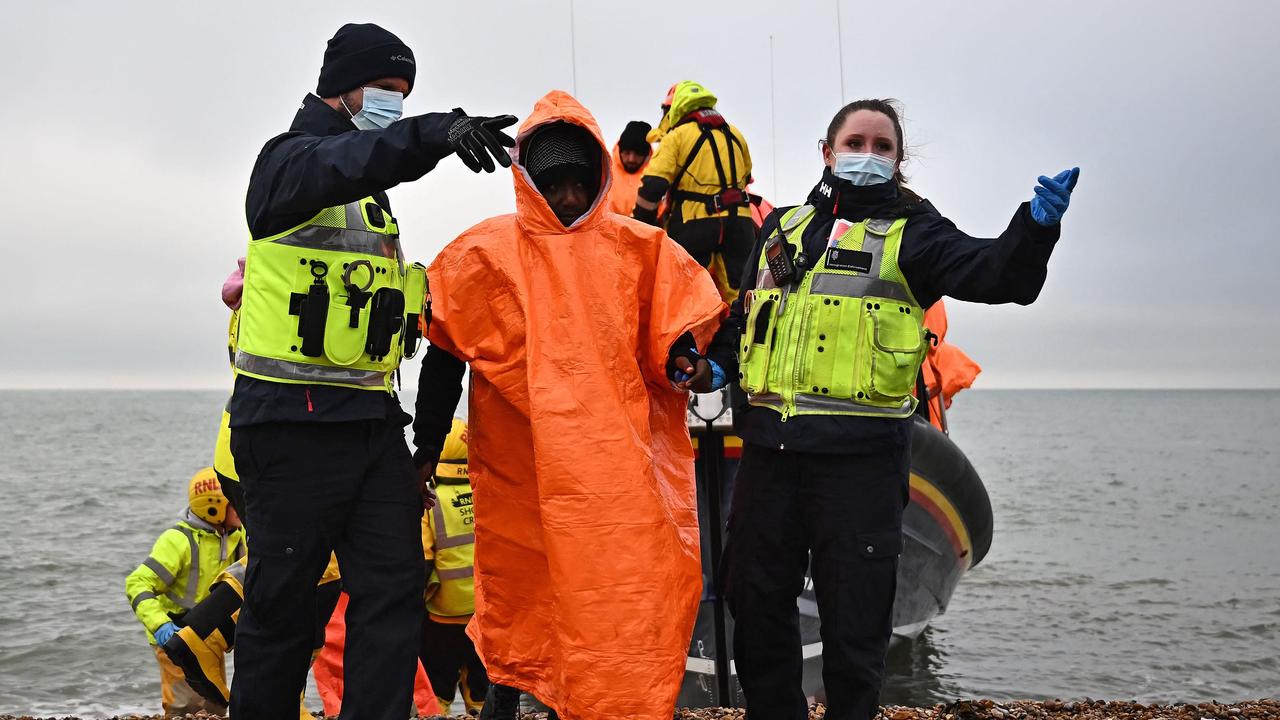 British Immigration Enforcement officers escort migrants on the shore at Dungeness on the southeast coast of England. Picture: AFP