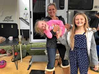 Harper Loadsman, who was the beneficiary of life-saving blood donations, in the arms of her mother Jana with sister Mia while camping in Ballina.